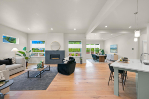 Bright open-concept living room with a fireplace, large windows, and a dining area in the background enough to notice the space flow.