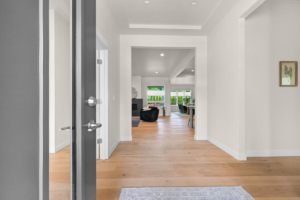 Open entry door leading into a bright, modern living space with hardwood floors and a view into the dining area.