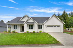 Front view of a white modern ranch-style house with a two-car garage, green lawn, and clear blue sky.