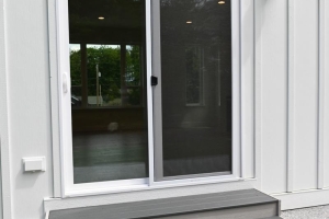 Sliding glass patio door with a three-step gray staircase leading to a white siding house exterior.