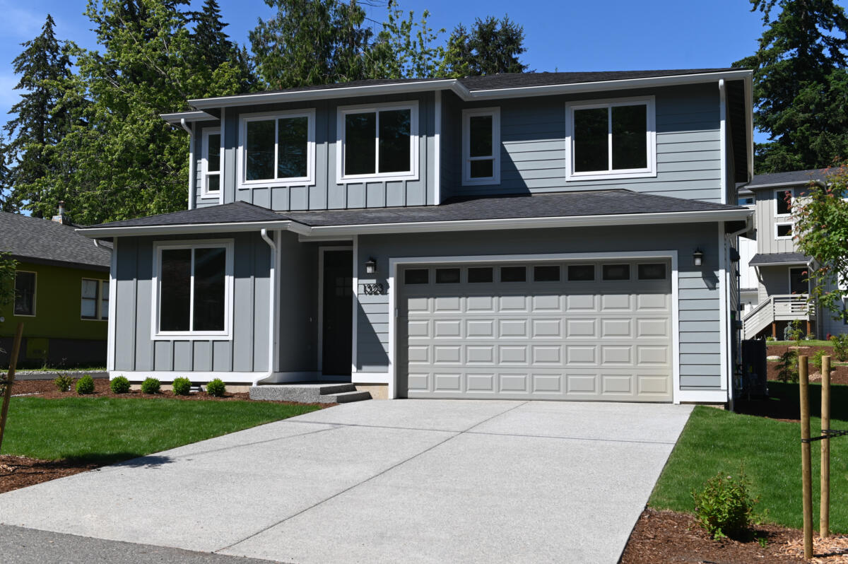 Two-story blue-gray suburban house with a white-trimmed two-car garage and a concrete driveway.